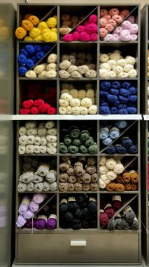 Dikiş iplikleri olan bir dolap, ipliklerden örgü örmek için yaratıcı bir el yapımı köşe. Gri raflarda renkli iplikleri olan bir örgü bölümü.