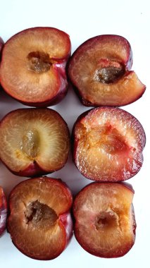 Yarım erik düzgünce sıralanır. Her erik sulu, kehribar renkli bir deriyle koyu kırmızı-mor bir ten sergiliyor. Doku yumuşak ve sulu görünüyor.