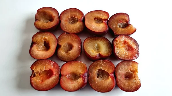 Koyu kırmızı-mor derili yarım erikler düzenli olarak sıralanır. Sulu, kehribar renkli derileri canlı deriyle çelişiyor. Ortadaki taş oyukları ortaya çıkıyor.