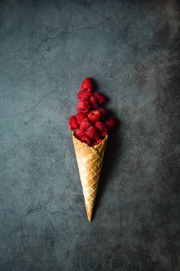 Koyu taştan arka planda waffle külahında taze böğürtlen, üst manzara. Sağlıklı yiyecekler ve çöl kavramı.