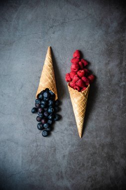 Koyu taştan arka planda waffle külahında taze böğürtlen, üst manzara. Sağlıklı yiyecekler ve çöl kavramı.