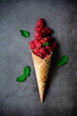 Koyu taştan arka planda waffle külahında taze böğürtlen, üst manzara. Sağlıklı yiyecekler ve çöl kavramı.