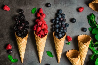 Koyu taştan arka planda waffle külahında taze böğürtlen, üst manzara. Sağlıklı yiyecekler ve çöl kavramı.