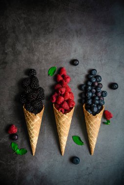 Koyu taştan arka planda waffle külahında taze böğürtlen, üst manzara. Sağlıklı yiyecekler ve çöl kavramı.