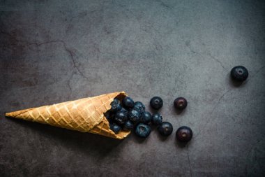 Koyu taştan arka planda böğürtlen ve krep külahları, üst manzara. Sağlıklı yiyecekler ve çöl kavramı.