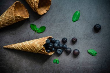 Koyu taştan arka planda böğürtlen ve krep külahları, üst manzara. Sağlıklı yiyecekler ve çöl kavramı.