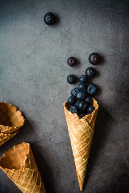Koyu taştan arka planda böğürtlen ve krep külahları, üst manzara. Sağlıklı yiyecekler ve çöl kavramı.