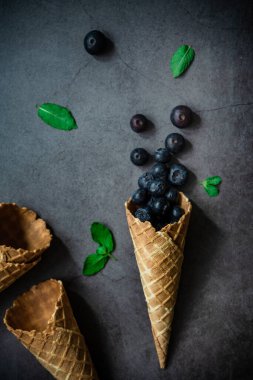 Koyu taştan arka planda böğürtlen ve krep külahları, üst manzara. Sağlıklı yiyecekler ve çöl kavramı.
