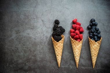 Koyu taştan arka planda waffle külahında taze böğürtlen, üst manzara. Sağlıklı yiyecekler ve çöl kavramı. Boşluğu kopyala.