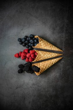 Koyu taştan arka planda waffle külahında taze böğürtlen, üst manzara. Sağlıklı yiyecekler ve çöl kavramı.