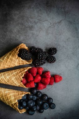 Koyu taştan arka planda waffle külahında taze böğürtlen, üst manzara. Sağlıklı yiyecekler ve çöl kavramı.