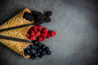 Koyu taştan arka planda waffle külahında taze böğürtlen, üst manzara. Sağlıklı yiyecekler ve çöl kavramı. Boşluğu kopyala.