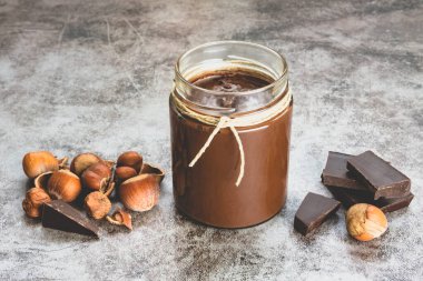 Homemade hazelnut chocolate butter, hazelnut, dark chocolate, on black stone background. The concept of cooking chocolate and nut paste.