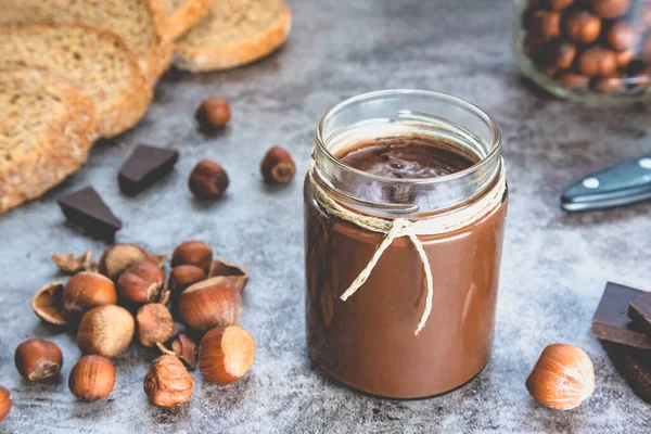 Homemade hazelnut chocolate butter, hazelnut, dark chocolate, on black stone background. The concept of cooking chocolate and nut paste.