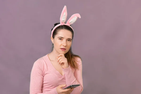Happy young woman wearing bunny ears with a phone in his hand.  Happy Easter shopping concept, shooting in a studio.