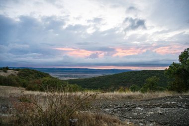Pembe, turuncu ve mor renkli bulutlar gölgeli tepeler ve ormanlar üzerinde sürükleniyor. Gün doğumunda ya da günbatımında dingin bir parıltı bırakıyorlar..