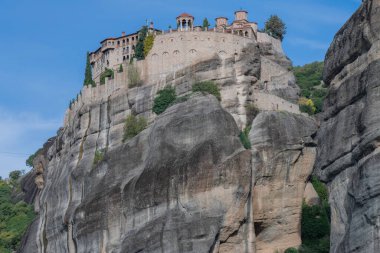 Tarihi bir manastır dik bir uçurumun tepesinde duruyor, taş mimarisini dramatik doğal jeolojiyle harmanlıyor..