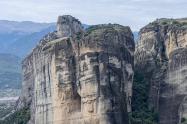 Meteora 'daki bir ormanlık vadiden yükselen yüksek bir kaya oluşumu