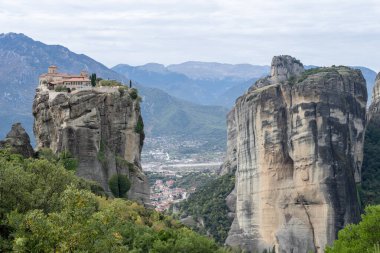 Manastırlar, yemyeşil ve uzak dağ sırtlarıyla çevrili, Meteoraların tepesinde yükselen kaya sütunları..