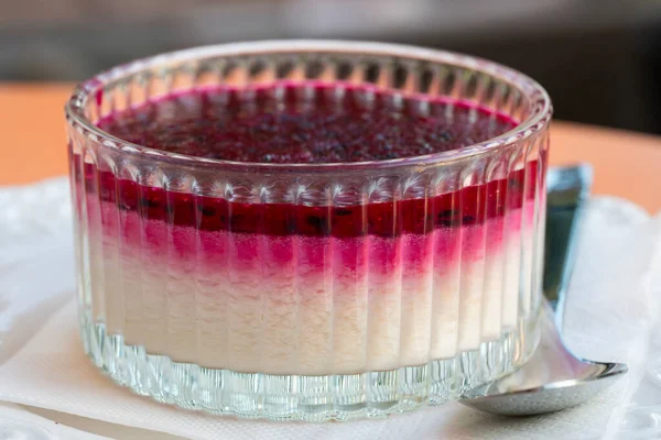 Kaburgalı cam bir tatlı tabağında koyu böğürtlenli kremalı muhallebi var..