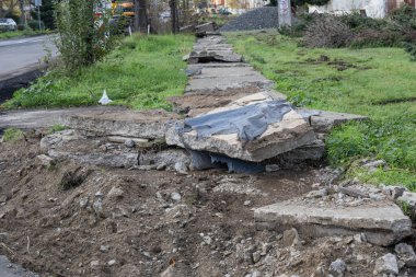 Yaya kısmının onarımını sembolize eden ağır hasar görmüş beton kaldırım.