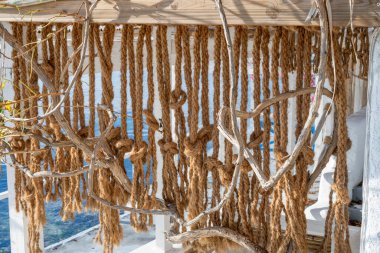 İp bükülmüş ve kuru dallar sakin bir rıhtımın yakınındaki ahşap bir çerçeveye asılmış..