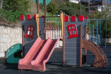 Şato temalı bir oyun alanı yapısında ikiz kırmızı slaytlar, bir tırmanma duvarı ve dekoratif siperler yer alıyor..