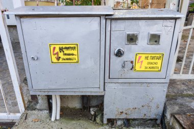 Bulgaristan 'ın yüksek voltajlı uyarı levhalarının bulunduğu iki gri elektrik kutusu beton bir üste duruyor.