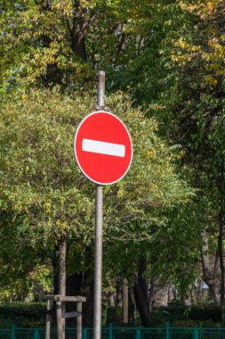 Ağaçlar ve yeşilliklerle çevrili metal bir direğin üzerinde kırmızı bir 