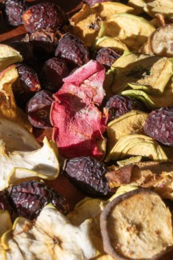 Kurumuş elma dilimleri ve parlak güneş ışığıyla aydınlatılan kırmızı gül kalçalarının dokulu arkaplanı..