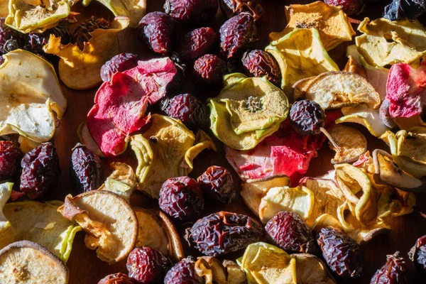 Kurumuş elma dilimleri ve parlak güneş ışığıyla aydınlatılan kırmızı gül kalçalarının dokulu arkaplanı..