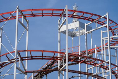 açık mavi gökyüzüne karşı kurulmuş karmaşık bir beyaz metal iskelet tarafından desteklenen kırmızı çelik hız treni pisti..