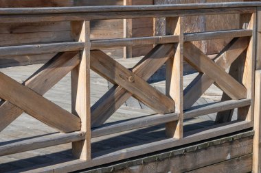 Dikdörtgen çerçeveler içinde X şeklinde çapraz dizayn içeren hafif bir ahşap korkuluk.