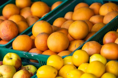 Sırayla dizilmiş taze portakal ve sarı elmalarla dolu yeşil plastik kasalar büyük ihtimalle bir markette ya da markette..