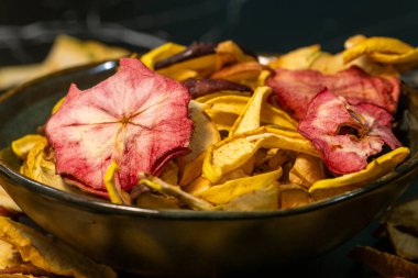 Kurutulmuş elma dilimleriyle dolu siyah bir kase.