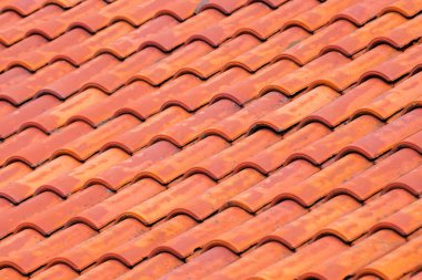 Geleneksel, hafif yıpranmış terracotta kil çatı kiremitleri, tekrarlayan, dalgalı geometrik desen ile sıralanmış görünür yaşlanma ve doku.