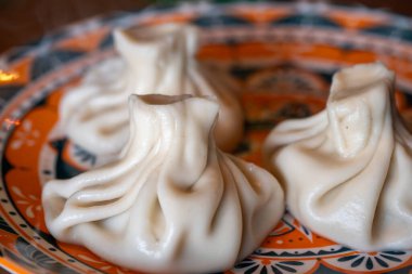 Geleneksel Gürcistan Khinkali köfteleri süslü turuncu ve mavi bir tabakta dizilmiş.