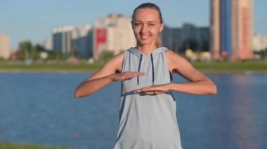 Spor giyim sektöründe genç ve fit bir kız dışarıda çalışıyor. Kadın parkta ve nehirde antrenman yapıyor. Sağlıklı ve spor yaşam tarzı.