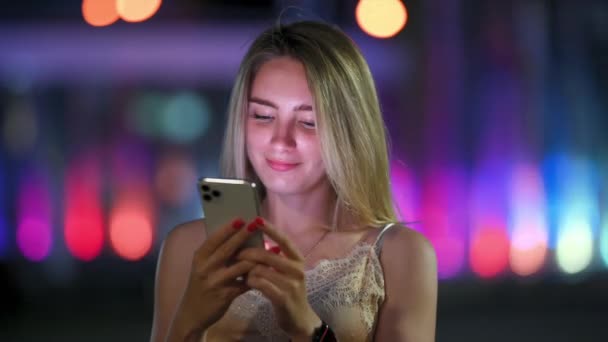 Menina Bonito Usa Smartphone Sorrisos Rua Noite Cidade Mulher Mensagens — Vídeo de Stock