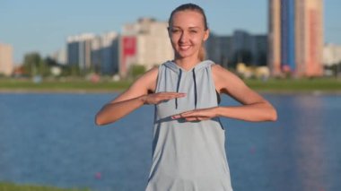 Spor giyim sektöründe genç ve fit bir kız dışarıda çalışıyor. Kadın parkta ve nehirde antrenman yapıyor. Sağlıklı ve spor yaşam tarzı.