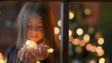 Elinde parlak çelenkler tutan ve hayal kuran mutlu tatlı kız. Noel ruhu. Yeni yıl ve tatil kavramı.