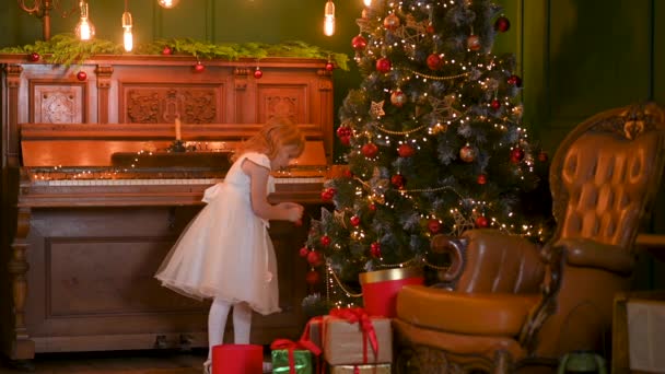 Boldog Kislány Aki Golyókkal Díszíti Karácsonyfát Rengeteg Ajándékdoboz Van Alatt — Stock videók