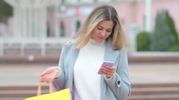 Joven Feliz Sonriente Shopaholic Mujer Caminando Calle Escribiendo Teléfono Inteligente — Vídeos de Stock