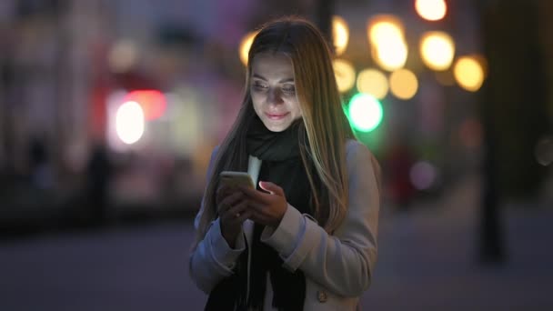 귀여운 소녀는스 Smiles 사용하여 도시의 나이트 스트리트에 거리에서 전화벨을 소식을 — 비디오