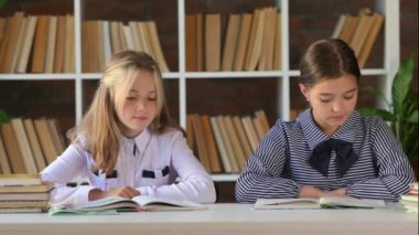 Genç liseli kızlar kütüphanede ya da evde masa başında oturup ödev yapıyor, kitap okuyorlar. çocuk eğitim kavramı