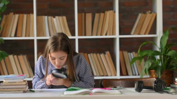 虫眼鏡をかけ机に座っている女子高生の肖像 子供は宿題を続けます 子ども教育の概念は — ストック動画