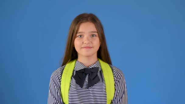 青いスタジオの背景に笑みを浮かべてリュックと学校の制服を着た幸せな10代の少女の肖像画 学校のコンセプトに戻り — ストック動画