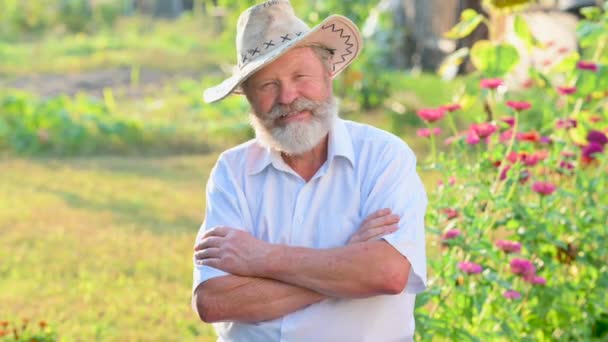 一个戴帽子 留着胡子的老人的近照 在一个乡村住宅的院子里看着摄像机 农民实人概念 — 图库视频影像