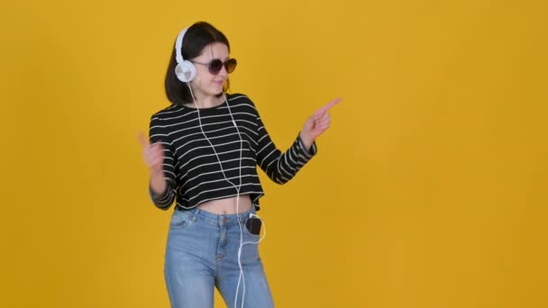 Portret Młodej Dziewczyny Okularach Przeciwsłonecznych Słucha Muzyki Słuchawkach Uśmiechem Wskazującym — Wideo stockowe