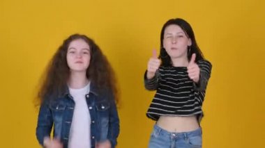 İki mutlu genç kız gülümsüyor ve baş parmak işareti yapıyor. İnsanlar yaşam tarzı kavramını hisseder